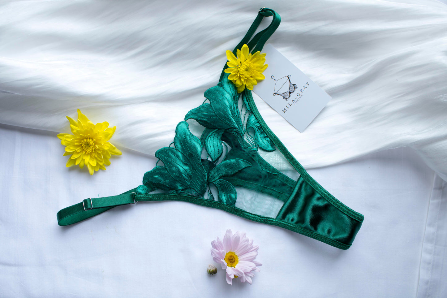 Green leaf-patterned lingerie set with flowers on a white fabric background